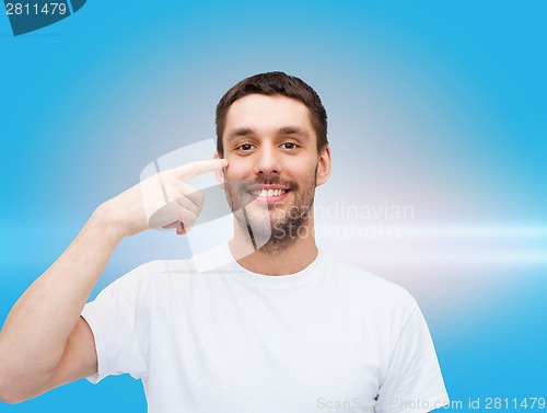 Image of smiling young handsome man pointing to eyes