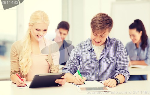 Image of two smiling students with tablet pc and notebooks