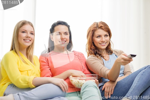 Image of three smiling teenage girl watching tv at home