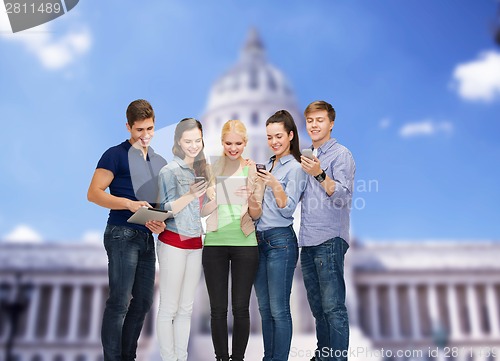 Image of smiling students using smartphones and tablet pc