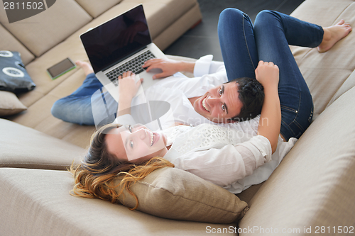 Image of young couple using laptop at home