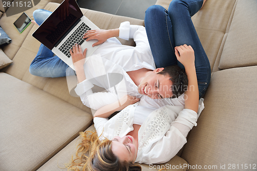 Image of young couple using laptop at home