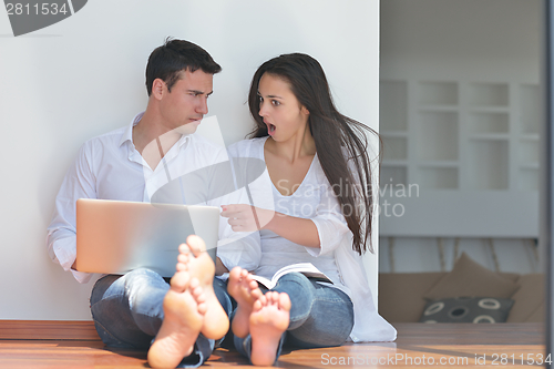 Image of young couple using laptop at home