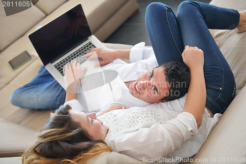 Image of young couple using laptop at home