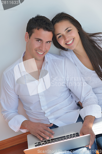 Image of young couple using laptop at home