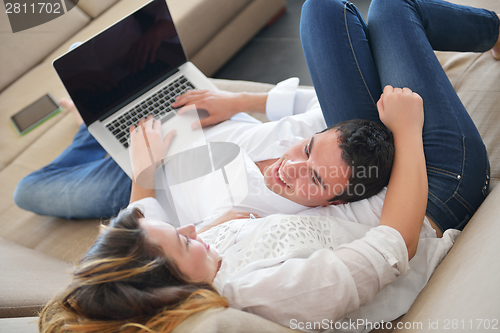Image of young couple using laptop at home