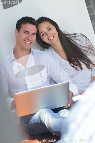 Image of young couple using laptop at home
