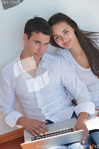 Image of young couple using laptop at home