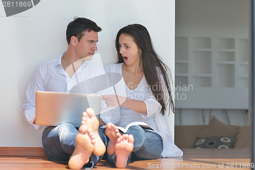 Image of young couple using laptop at home