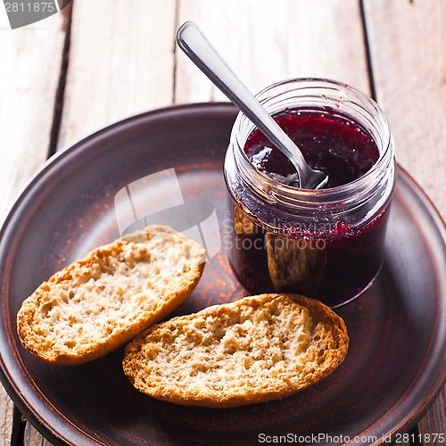 Image of black currant jam in glass jar and crackers 