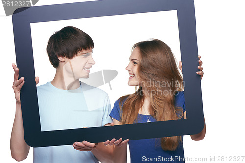 Image of Happy couple holding tablet frame and looking at each other