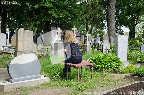 Image of Sorrow woman shrinked near father husband tomb 