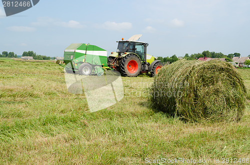Image of tractor bailer collect hay in agriculture field 