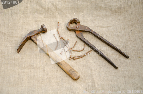 Image of hammer with nail and pliers lying on linen texture 