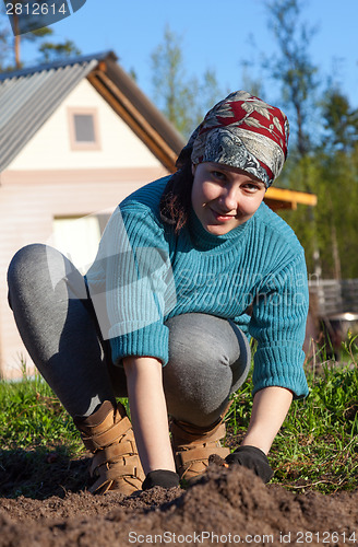 Image of A young girl working in the garden at the cottage 