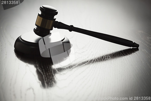 Image of Dramatic Gavel Silhouette on Reflective Wood