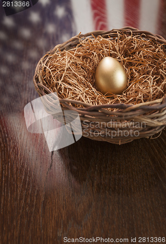 Image of Golden Egg in Nest with American Flag Reflection on Table