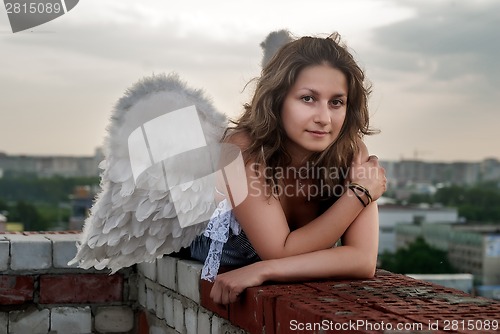 Image of Attractive woman with angel wings on roof
