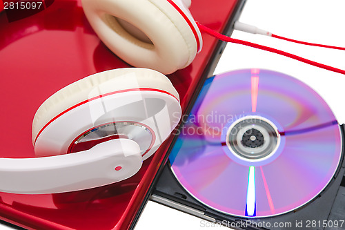 Image of Portable computer with DVD disc and red white headphones