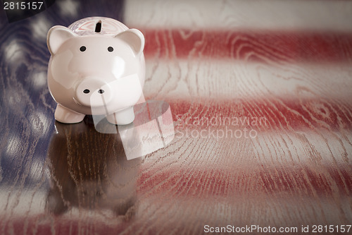 Image of Piggy Bank with an American Flag Reflection on Table