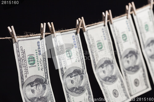 Image of Hundred Dollar Bills Hanging From Clothesline on Dark Background