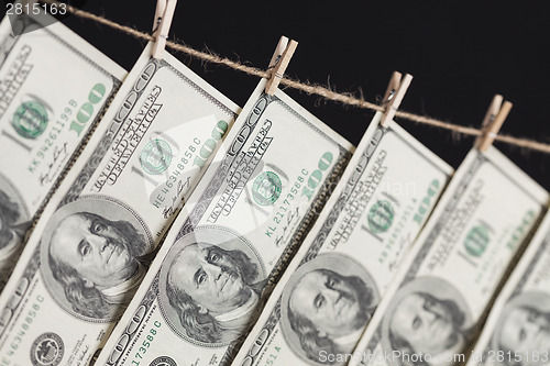 Image of Hundred Dollar Bills Hanging From Clothesline on Dark Background