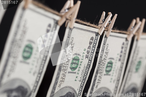 Image of Hundred Dollar Bills Hanging From Clothesline on Dark Background