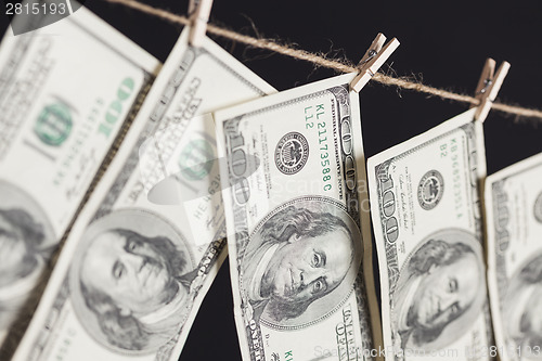 Image of Hundred Dollar Bills Hanging From Clothesline on Dark Background
