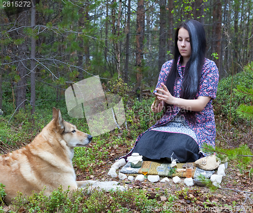 Image of Girl witch conjures in the woods. Near a huge dog 