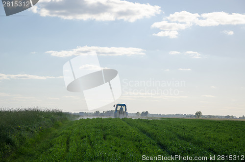 Image of Tractor spray field with chemicals and worker man 