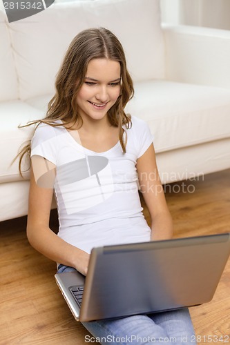 Image of smiling teenage girl with laptop computer at home