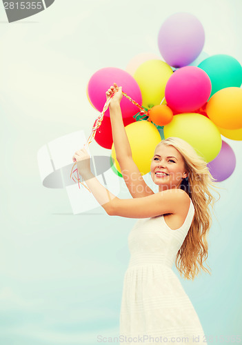 Image of smiling woman with colorful balloons outside