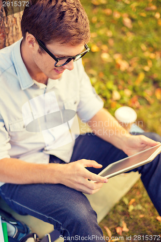 Image of smiling male student in eyeglasses with tablet pc