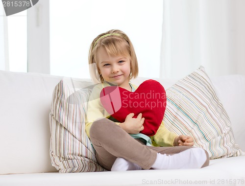 Image of smiling little girl with red heart at home