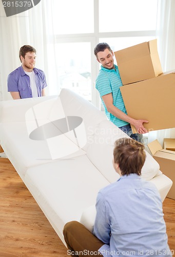 Image of smiling friends with sofa and boxes at new home