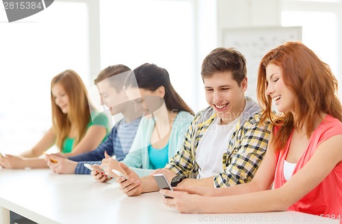 Image of smiling students with smartphones at school