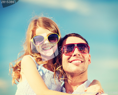 Image of happy father and child in sunglasses over blue sky