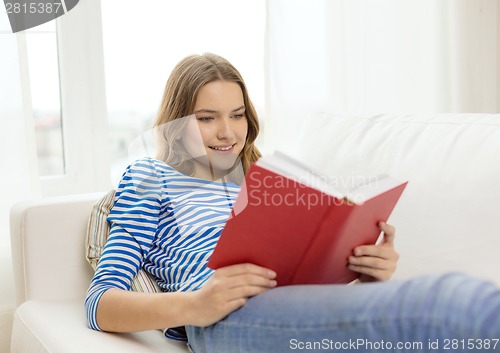 Image of smiling teenage girl reading book on couch