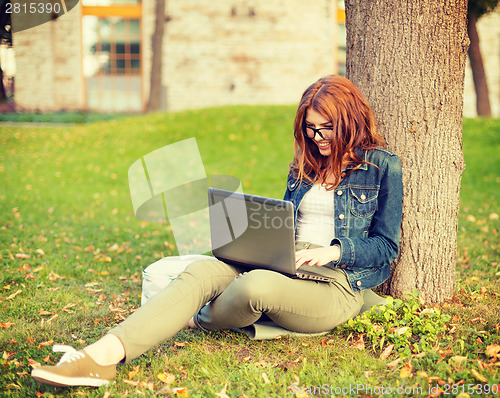 Image of smiling teenager in eyeglasses with laptop