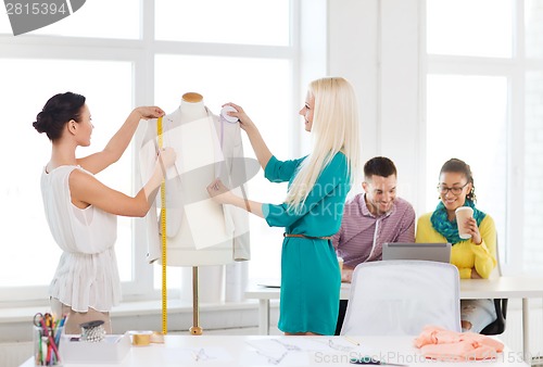 Image of fashion designers measuring jacket on mannequin
