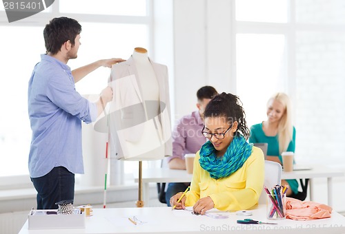 Image of smiling fashion designers working in office