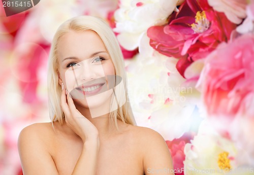 Image of smiling young woman touching her face skin