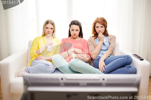 Image of three sad teenage girl watching tv at home