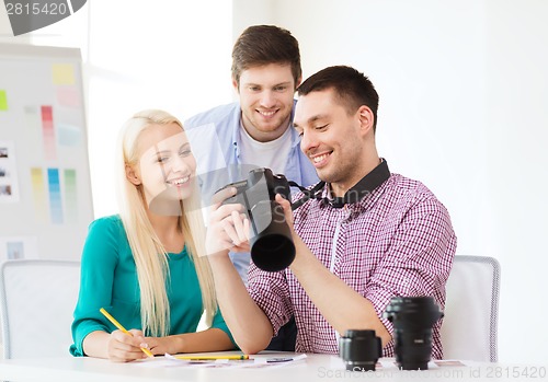 Image of smiling team with photocamera working in office