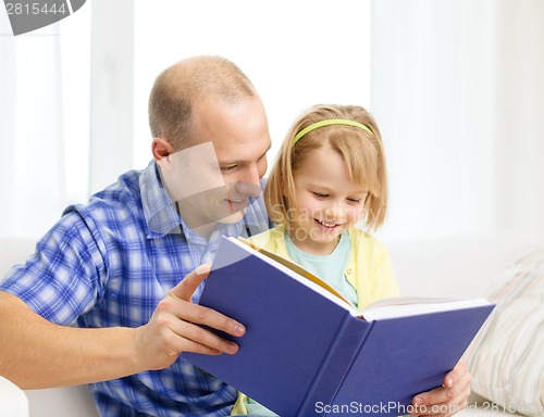 Image of smiling father and daughter with book at home