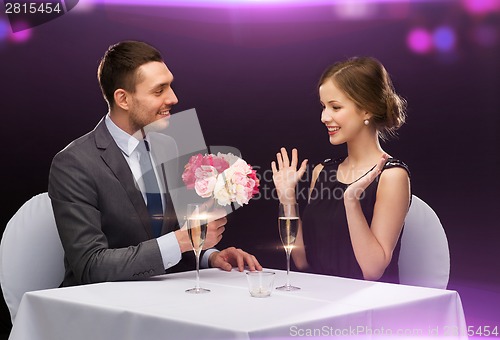 Image of smiling man giving flower bouquet to woman