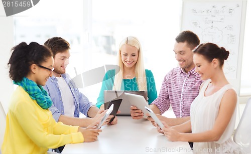 Image of smiling team with table pc and laptop in office