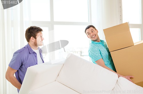 Image of smiling friends with sofa and boxes at new home