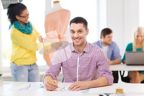 Image of smiling fashion designers working in office