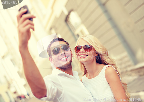 Image of smiling couple with smartphone in the city